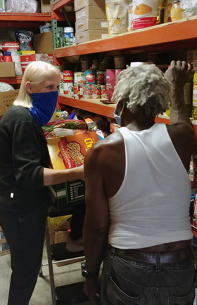 The Rev. Faith Fowler, executive director of Cass Community Social Services and senior pastor of Cass Community United Methodist Church in Detroit, speaks with volunteer Ke Ke Sacada while preparing to load a van for free grocery deliveries. Photo by Samantha Funk.