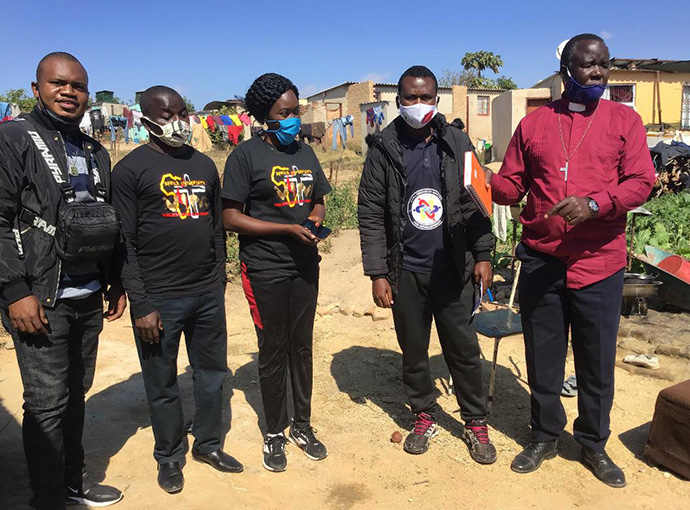 Africa University students Cesar Lodiha Akoka from Congo (from left), Barde Danjuma from Nigeria, Everlyne Kukah Esther from Kenya, Fiston Okito from Congo and the Rev. Joseph Charinge gather before distributing food to families in Gimboki, Zimbabwe, a preaching point community of St. James Dangamvura United Methdoist Church. Charinge, pastor of Gimboki UMC, said the Feed a Family campaign started by the students has resulted in six people joining his church. Photo by Chenayi Kumuterera, UM News.