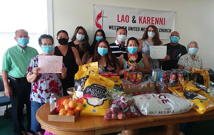 The Lao and Karenni United Methodist Church of the Upper New York Conference say “thank you” for their AALM Resiliency Fund grant.  Displayed in front of them are some of the groceries purchased with the grant, which were distributed to families in need. Photo by the Rev. Sonexay Chathasone. 