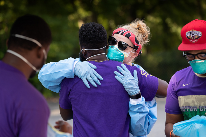 Volunteer Hannah LaBrecque (center) hugs a fellow volunteer as they don protective equipment before the opening of a drive-thru testing site for COVID-19 at St. Luke Christian Methodist Episcopal Church in Nashville. LaBrecque regularly joins a volunteer team from Meharry Medical College in Nashville to provide pop-up testing sites on Saturdays at area churches. Photo by Mike DuBose, UM News.