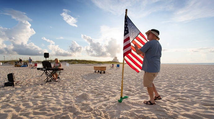 Bob Cristopher unfurls the U.S. flag prior to the Galilean Beach Service while Sherrie Lynn Brewer warms up on the keyboard. Photo by Mike DuBose, UM News.