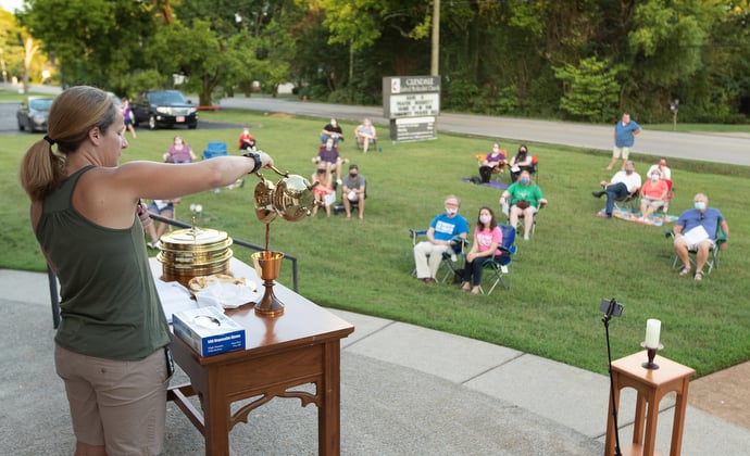 The Rev. Steph Dodge blesses the elements of Holy Communion during an outdoor worship service at Glendale United Methodist Church in Nashville, Tenn. Photo by Mike DuBose, UM News.