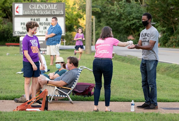 Laura Kreiselmaier serves Holy Communion to James Poland (right) during an outdoor worship service at Glendale United Methodist Church in Nashville, Tenn. Photo by Mike DuBose, UM News.