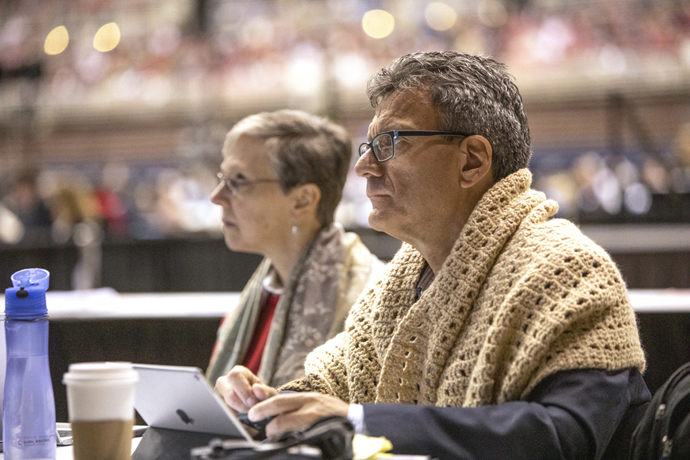 Agency top executives Harriet J. Olson with United Methodist Women and Thomas Kemper (wrapped in a prayer shawl) with Global Ministries listen to speakers at the 2019 United Methodist General Conference. Both agencies are coping with decreases in denomination giving  File photo by Kathleen Barry, UM News.