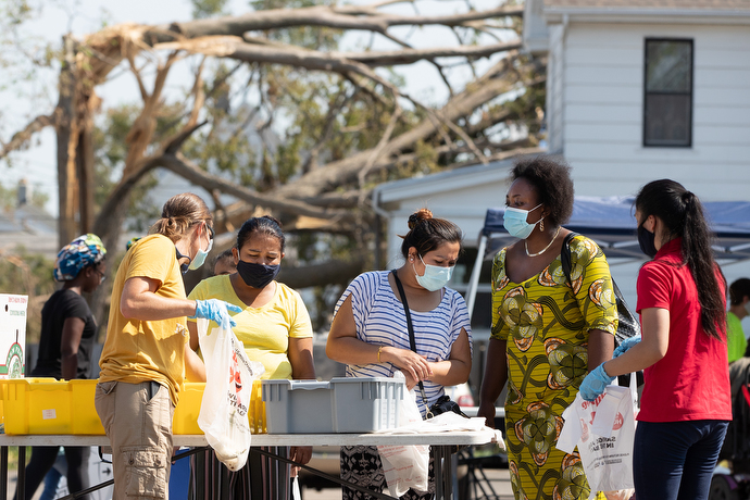 Community members select donated food items with the help of volunteers at a neighborhood resource center in the parking lot of St. Paul’s United Methodist Church in Cedar Rapids, Iowa. The city-run center provided access to relief services, clothing and other donated items, in addition to food. Photo by Mike DuBose, UM News.