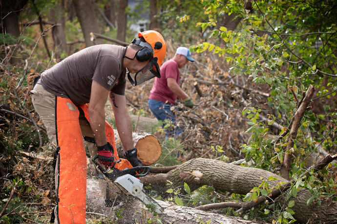 United Methodist volunteers Darren Garrett (front) and Dale Krohn clear downed trees at a home in Cedar Rapids, Iowa, following an Aug. 10 derecho. Photo by Mike DuBose, UM News.