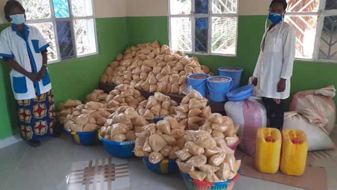 Infirmière Titulaire, Véronique Nyembo (à gauche) et la chargée de nutrition, Marie José Tshoo (à droite) avec des intrants pourla prise en charge nutritionnelle des enfants du Centre. Dans les emballages, il y'a un mélange de : farines de maïs, de soja, du sucre huile de palme. Dans des sceaux bleu il y'a la pâte d' arachide. Cette équipe travaille pour envoyé des aliments au CRN de Diengenga, de Dingele, Djalo et Bena Dibele. Photo par François Omanyondo.