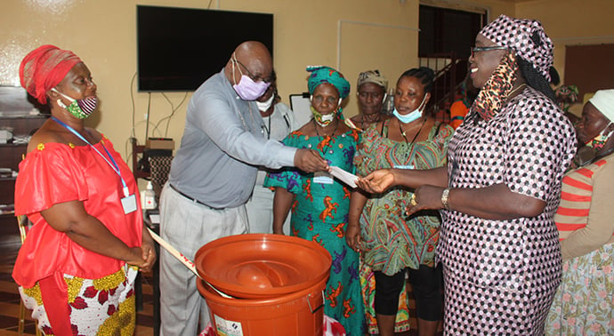 The Rev. Dr. Matthew A. Jaiah of S.T. Nagbe United Methodist Church presents a voucher of $350 to women of the Monrovia District on behalf of the leadership of United Methodist Women in Liberia. The seed money will help the women kick off the Village Saving Scheme in their area. Photo by E Julu Swen, UM News. 