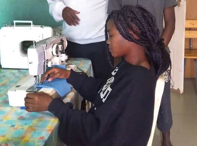 Winnet Mandikisi, 19, works at a sewing machine at Home of Hope, the orphanage at Nyadire United Methodist Mission in Mutoko, Zimbabwe. Mandikisi, a college student, has been leading efforts to teach fellow orphans how to make masks to fight against COVID-19. Photo by Chenayi Kumuterera, UM News.  