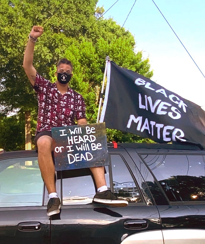 Derian Wilson who protests racism regularly in Macon, Ga., sits atop an SUV during a demonstration. Photo courtesy of Derian Wilson.