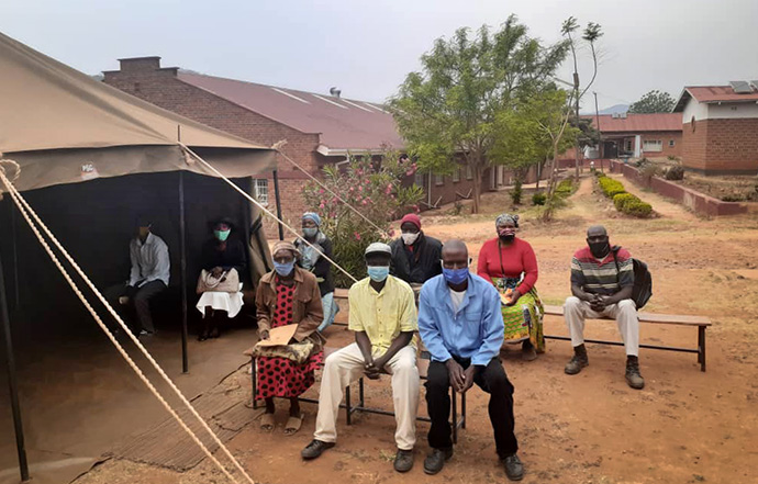 Patients wait to be seen inside and outside a screening tent set up at Old Mutare Mission Hospital in Mutare, Zimbabwe. The United Methodist Church’s mission hospitals are using the tents to screen and isolate patients to help stop the spread of the coronavirus. Photo by Kudzai Chingwe, UM News.