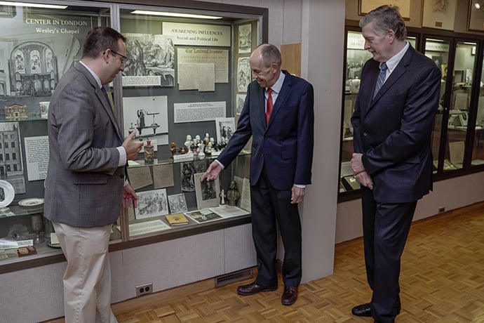 The Rev. Terry Bevill (center), president of the Friends of the World Methodist Museum, visits with Anthony Elia (left), director of Bridwell Library, and the Rev. Craig C. Hill, dean of the Perkins School of Theology, during the final meeting of the Friends of the World Methodist Museum in Lake Junaluska, N.C. Bevill was pointing out a copy of John Wesley’s famous work “Primitive Physick: Or, An Easy and Natural Method of Curing Most Diseases.” Photo by Ryan Hipps.