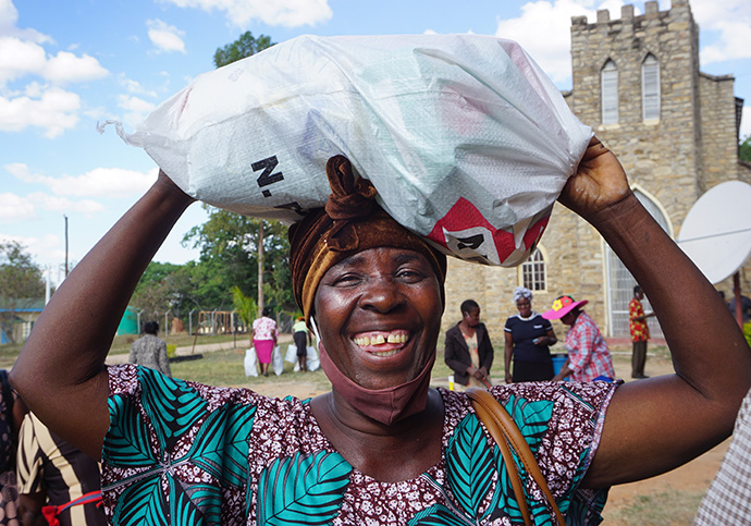 Monica Maposa carries a bundle of donated food and sanitation supplies she received during a distribution at Murewa Center United Methodist Church outside Harare, Zimbabwe. Photo by Kudzai Chingwe, UM News.