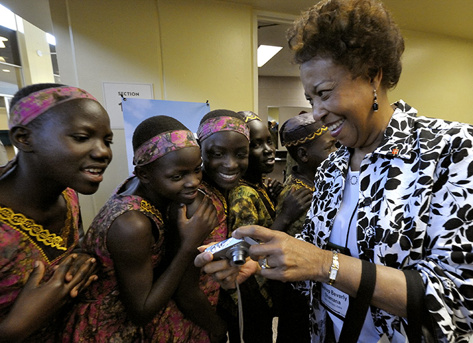 Bishop Beverly Shamana shares photos with members of the Hope for Africa Children's Choir, which performed at the 2008 United Methodist General Conference in Fort Worth, Texas. File photo by Paul Jeffrey, UM News. 