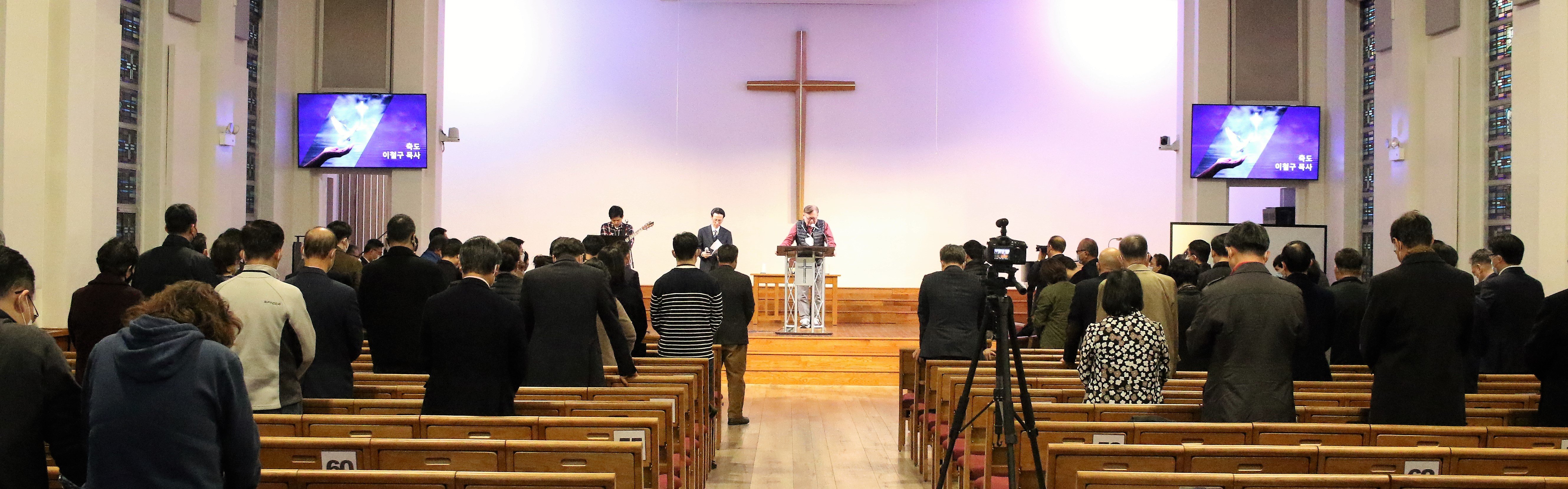 <카리스마 리바이벌>의 개회예배에서 축도 중인 이성현 목사와 고개 숙여 기도하는 목회자들. 사진, 김응선 목사, 연합감리교뉴스. 