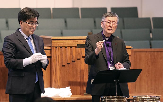 The Rev. Chul Goo Lee (left), president of the Association of Korean Churches in The United Methodist Church, and retired Bishop Youngjin Cho, interim pastor of the Korean Church of Atlanta, prepare to serve Holy Communion during the first day of the association’s meeting. Photo by the Rev. Thomas Kim, UM News.