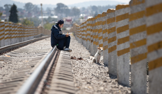 José,a migrant from Argentina, sits with his dog on the railroad tracks behind the Casa de la Sagrada Familia shelter in Apizaco, Mexico, some 600 miles northwest of the Guatemalan border. Photo by Mike DuBose, UM News.