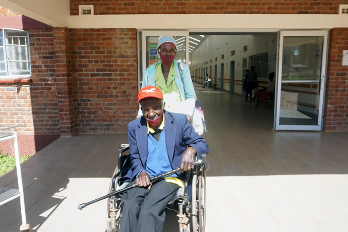 Elithia Mukoma pushes her husband David Mukoma’s wheelchair while leaving the new outpatient department after getting treatment at Old Mutare Mission Hospital in Mutare, Zimbabwe. The new state-of-the-art outpatient department is one of several updates to the institution that was founded in 1903. Photo by Kudzai Chingwe, UM News.