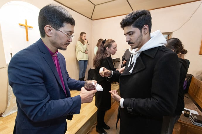 Bishop Eduard Khegay (left) and the Rev. Nellya Shakirova (wearing black dress) offer Holy Communion at Bishkek United Methodist Church. Photo by Mike DuBose, UM News.