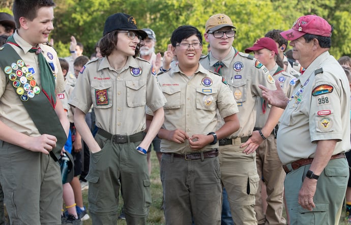 Scoutmaster Mike Warren (right) visits with scouts from Troop 398 while they wait for the evening flag ceremony to begin at the Boxwell Scout Reservation. Photo by Mike DuBose, UM News.